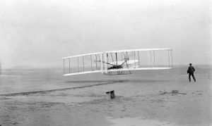 Seconds into the first airplane flight, near Kitty Hawk, North Carolina, on December 17, 1903. Orville Wright is at the control of the machine. Wilbur Wright, his brother, alongside to help balance the machine.